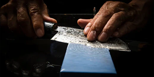 Affûtage manuel d'un couteau de cuisine sur une pierre à aiguiser.