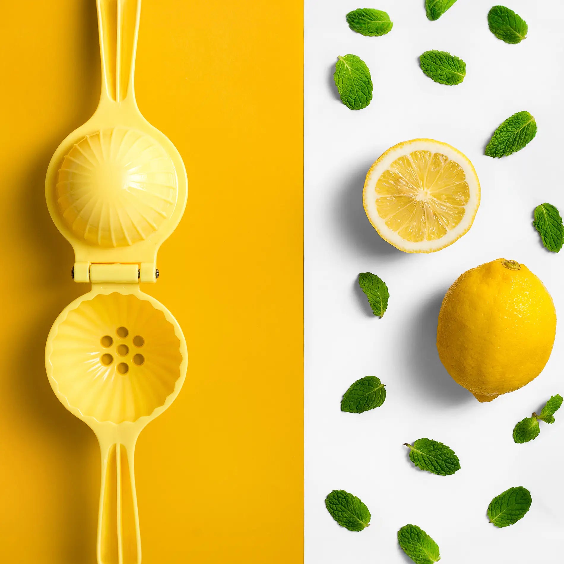 Presse citron avec sur un fond jaune avec des feuilles de menthe et des citrons coupés