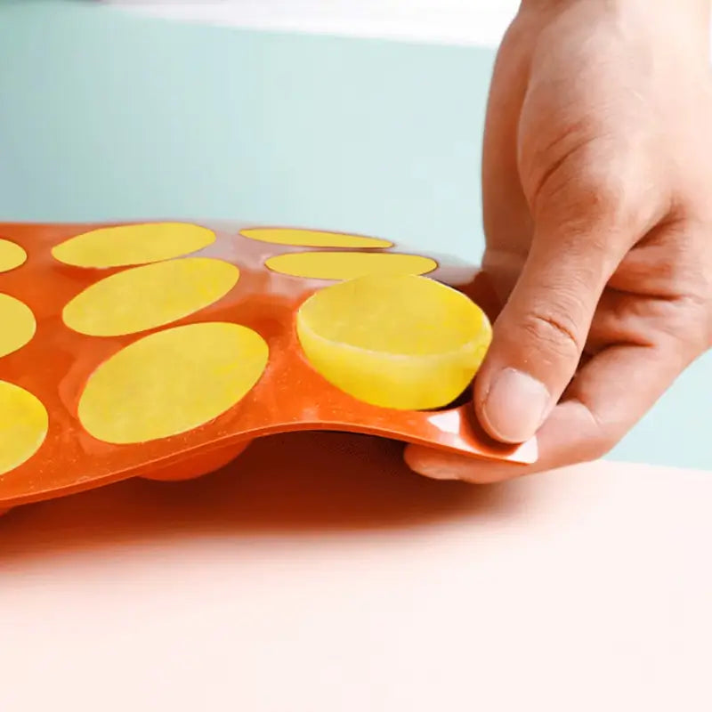 Une main démoulant un gâteau jaune d’un moule en silicone rouge souple, illustrant la facilité d’utilisation pour pâtisseries.